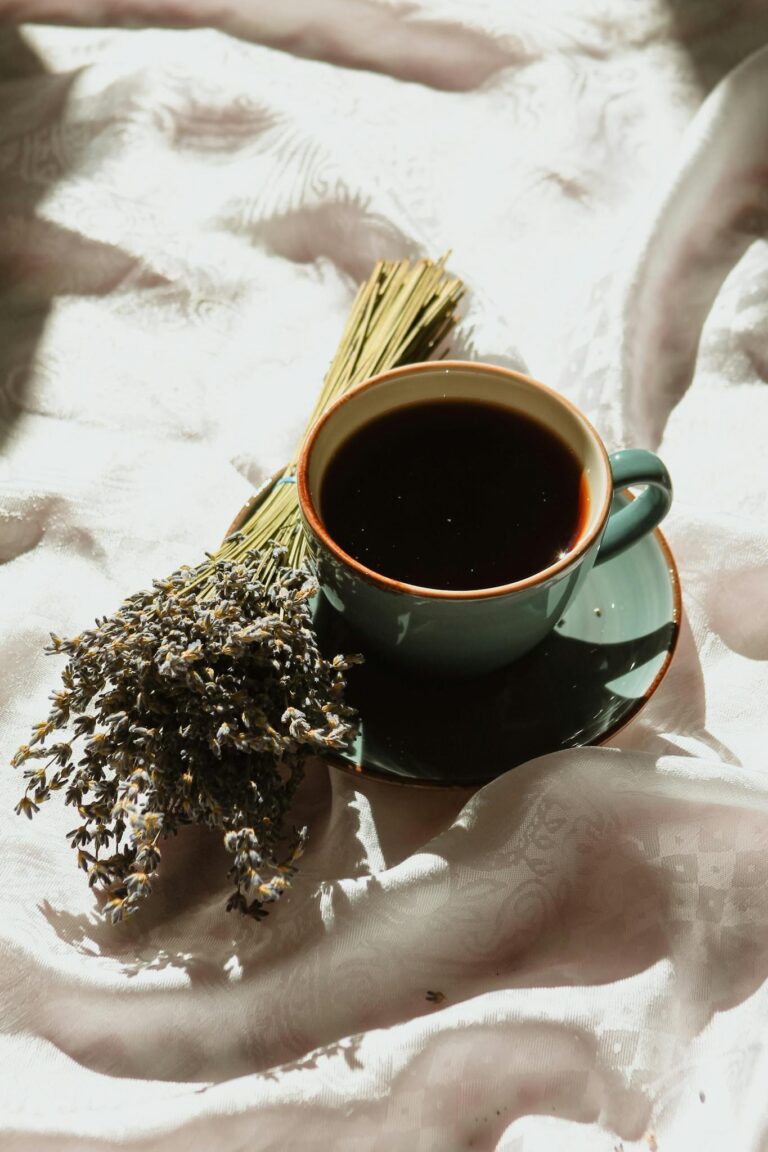 A cup of black coffee paired with lavender on white fabric, evoking relaxation.